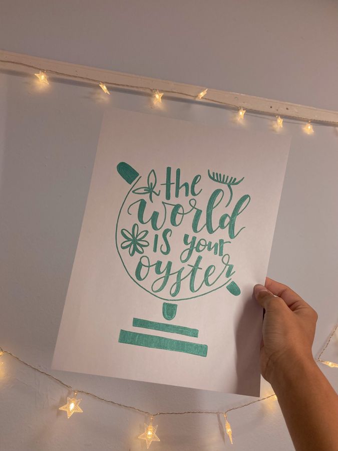 A calligraphy piece Chloe made that reads the world is your oyster, lettered inside a globe