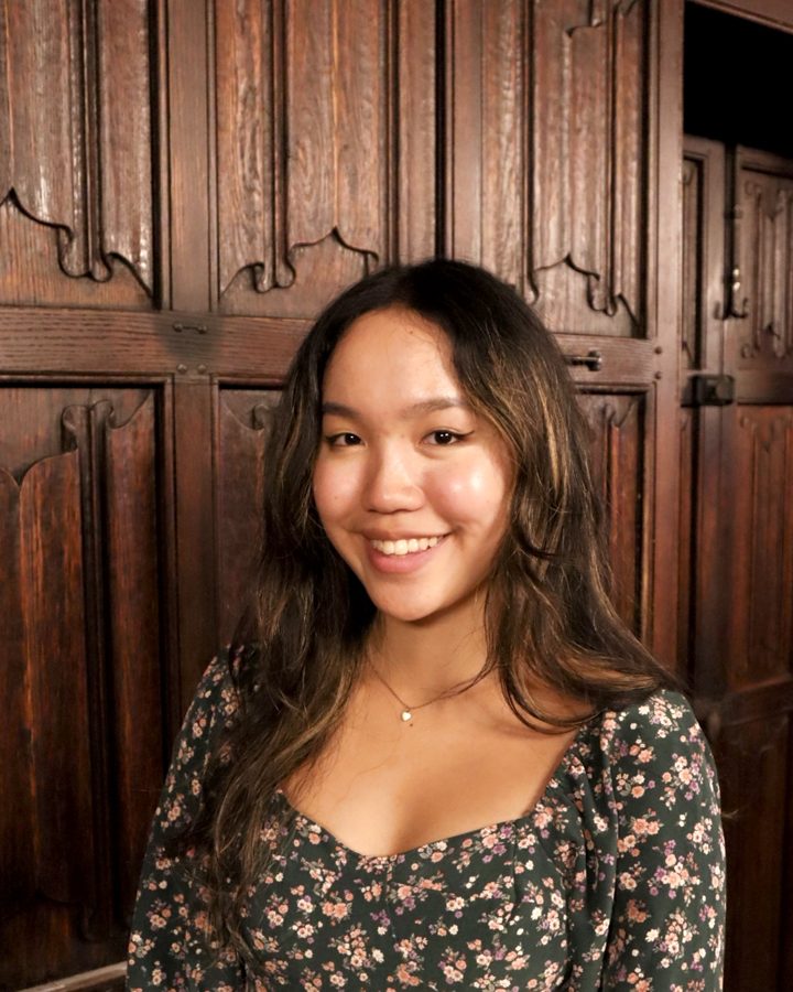 Chloe in a floral dress in front of carved wood paneling